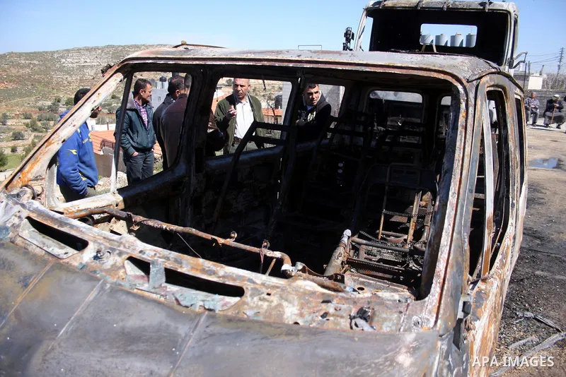 Palestinians stand next to vehicles they said were set on fire by Jewish settlers in retaliation following a deadly attack on a settler family on Friday, in the West Bank in Ramallah, Monday, March 14, 2011. The U.S. Emb...