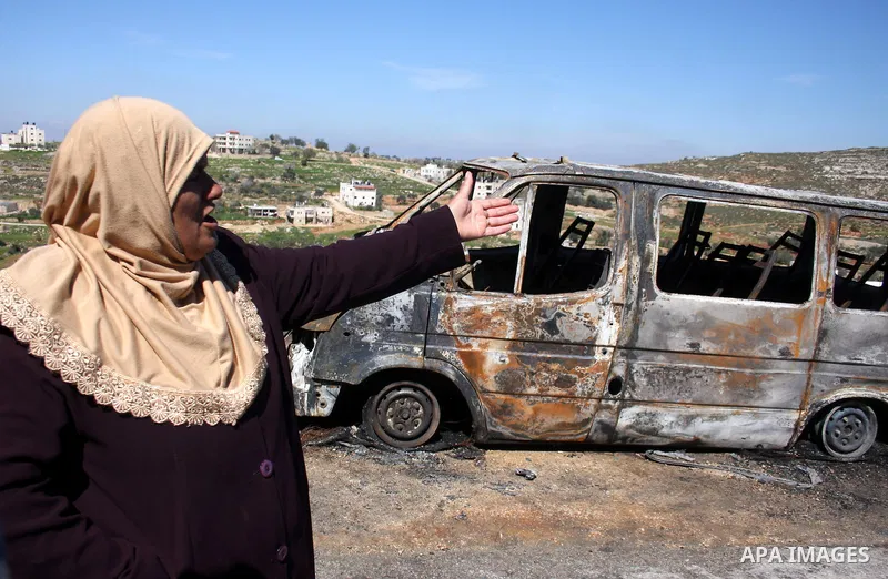 Palestinians stand next to vehicles they said were set on fire by Jewish settlers in retaliation following a deadly attack on a settler family on Friday, in the West Bank in Ramallah, Monday, March 14, 2011. The U.S. Emb...