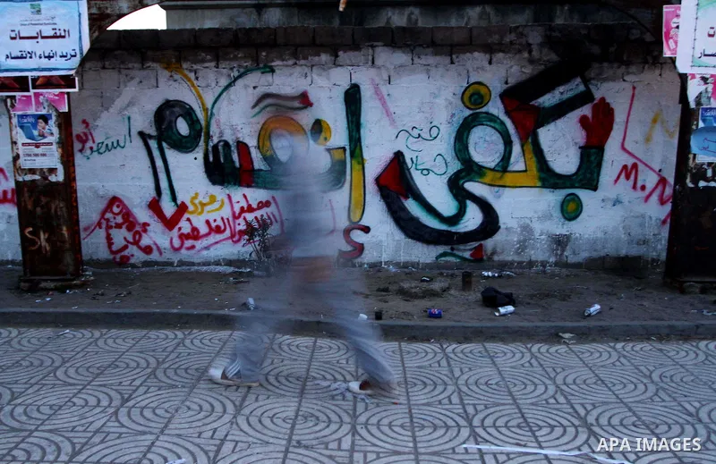 A Palestinian youth walks past a message that reads enough with divisions on a wall during a march calling for a reconciliation between the rival Palestinian leading factions Hamas in Gaza and Fatah in the West Bank, in...