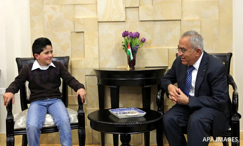 Palestinian Prime Minister Salam Fayyad meets the child Issam Bashiti in the West Bank city of Ramallah March 15, 2011. Photo by Mustafa Abu Dayeh