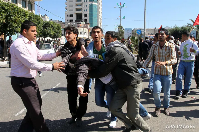 Palestinian demonstrators carry a wounded youth during brief clashes between Hamas supporters and protestors supporting other Palestinian factions, during a rally calling for Palestinian political unity between Gaza's Ha...