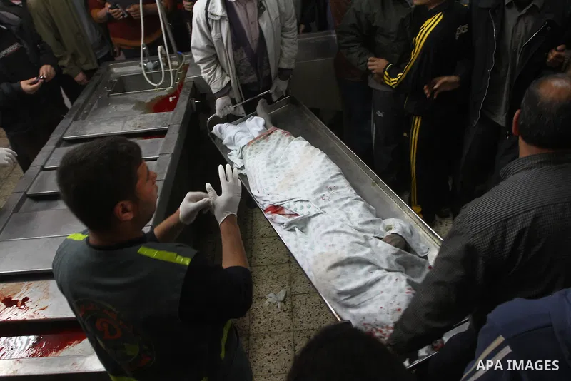 Palestinians stand next to the body of a Hamas militant killed in an Israeli air strike on a Hamas training camp, after is was brought to the morgue of Shifa hospital in Gaza City, Wednesday, March 16, 2011. Israeli figh...