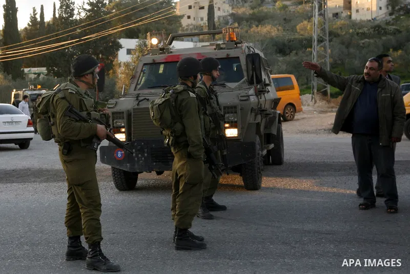 Israeli soldiers stand guard near the Israeli settlement of Qadumim between Qalqilya and Nablus in the West Bank after settlers torched the cars of two Palestinians working inside the settlement on March 17, 201. Photo b...