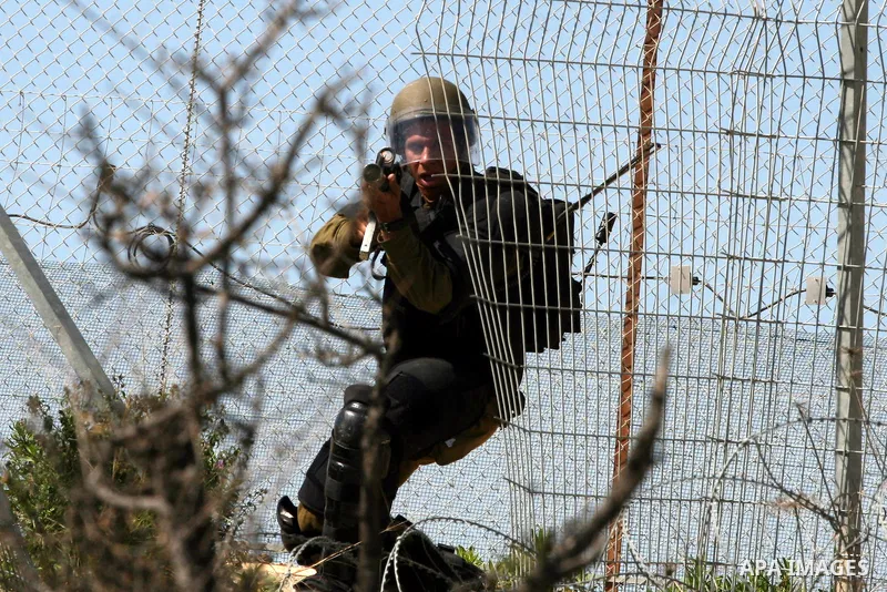 An Israeli soldier fires tear gas canister towards Palestinian youths during clashes following a weekly demonstration against Israel's separation barrier in the West Bank village of Bilin on March 18, 2011. Photo by Issa...