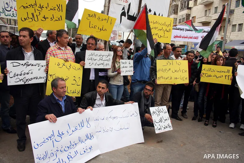 Journalists and photographers hold banners during a protest in the West Bank city of Ramallah, 20 March 2011 following the raid on Reuters office by security forces in Gaza city on 19 March. Photo by Issam Rimawi