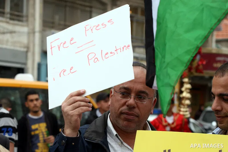 Journalists and photographers hold banners during a protest in the West Bank city of Ramallah, 20 March 2011 following the raid on Reuters office by security forces in Gaza city on 19 March. Photo by Issam Rimawi