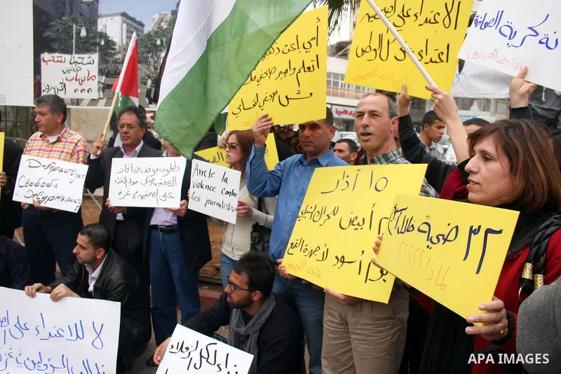 Journalists and photographers hold banners during a protest in the West Bank city of Ramallah, 20 March 2011 following the raid on Reuters office by security forces in Gaza city on 19 March. Photo by Issam Rimawi