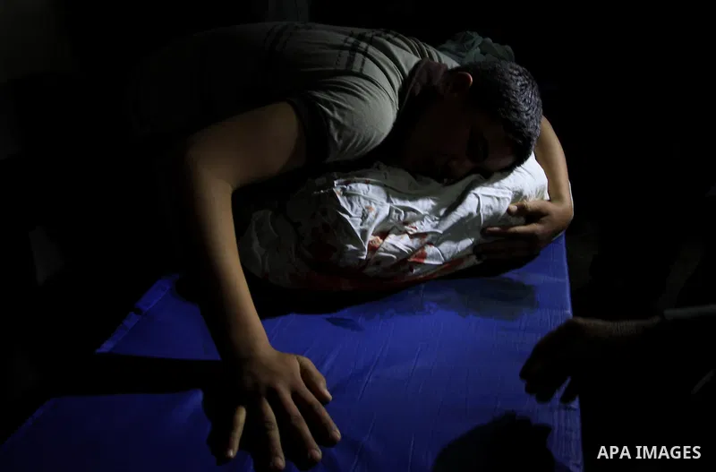 Palestinians stand next to the body of a Palestinian killed in an Israeli shells, after was brought to the morgue of Shifa hospital in Gaza City, Tuesday, March 22, 2011. Israeli tank fire struck a house in the Gaza Stri...