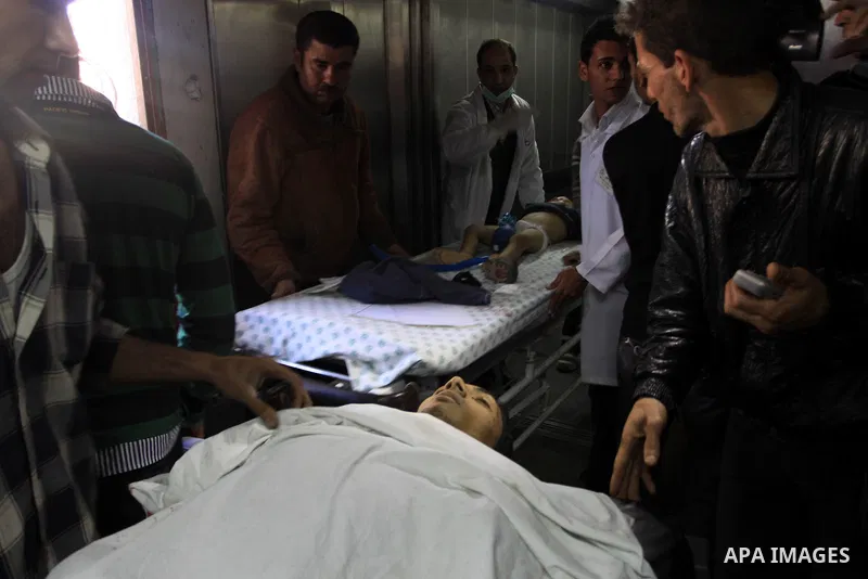 Palestinians stand next to the body of a Palestinian killed in an Israeli shells, after was brought to the morgue of Shifa hospital in Gaza City, Tuesday, March 22, 2011. Israeli tank fire struck a house in the Gaza Stri...
