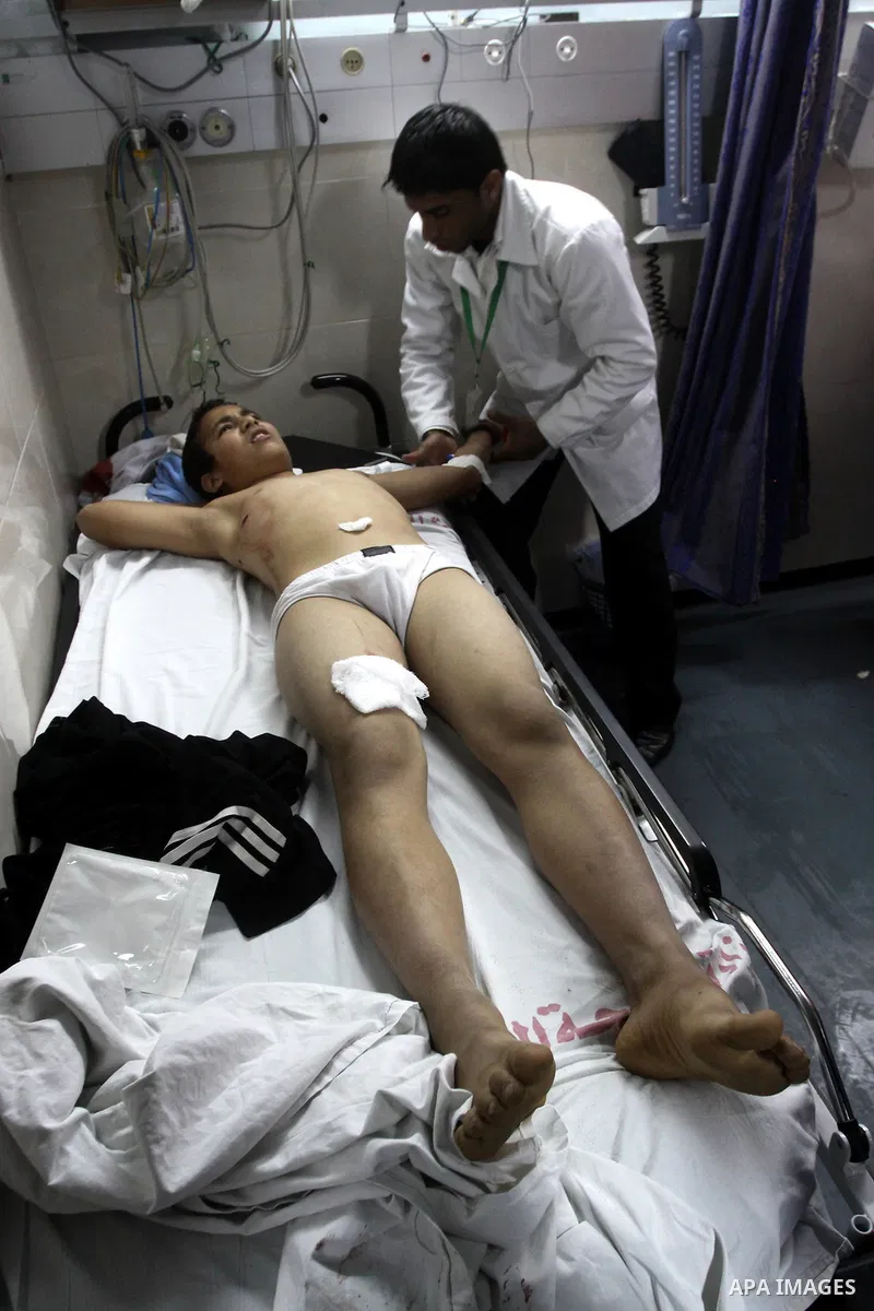 Palestinian medics stand next to a Palestinian injured in an Israeli shells, after was brought to the Shifa hospital in Gaza City, Tuesday, March 22, 2011. Israeli tank fire struck a house in the Gaza Strip on Tuesday, k...