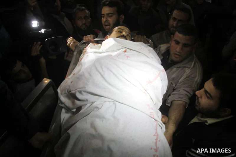 Palestinians stand next to the body of a Palestinian killed in an Israeli shells, after was brought to the morgue of Shifa hospital in Gaza City, Tuesday, March 22, 2011. Israeli tank fire struck a house in the Gaza Stri...