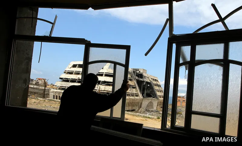A Palestinian adjusts his broken windows in front of destroyed security office in Gaza City, on March 25, 2011, as Israeli aircraft attacked four targets in the Gaza Strip during the night, lightly wounding three people,...