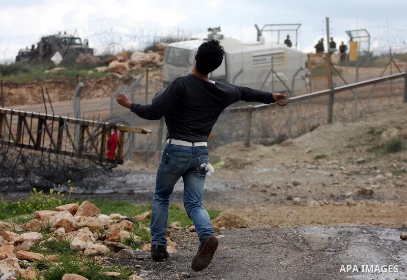 A Palestinian youth throws stones at Israeli forces during clashes following a weekly demonstration against Israel's separation barrier in the West Bank village of Bilin on March 25, 2011. Photo by Issam Rimawi