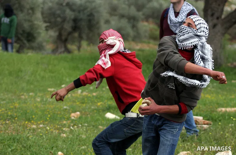 Palestinian youths throw stones at Israeli forces during clashes following a weekly demonstration against Israel's separation barrier in the West Bank village of Bilin on March 25, 2011. Photo by Issam Rimawi