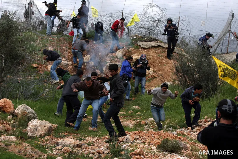 Palestinian protesters run to avoid tear gas fired by Israeli soldiers during clashes following a weekly demonstration against Israel's separation barrier in the West Bank village of Bilin on March 25, 2011. Photo by Iss...