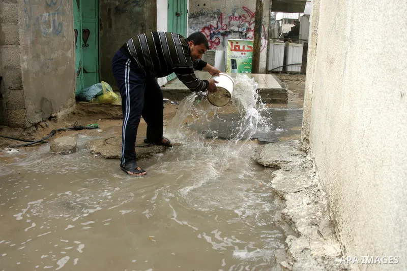 Palestinian man evacuates the rain water in front of his house in the Rafah refugee camp southern Gaza Strip on March 25, 2011.Photo Abed Rahim Khatib.