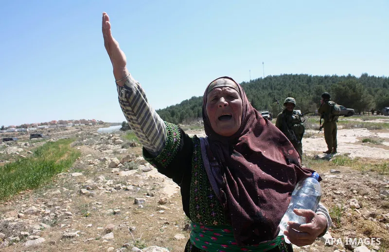 A Palestinian woman quarrels with Israeli soldiers during a protest against Jewish settlers in the West Bank village of Yatta, south of the West Bank city of Hebron, on 26 March 2011.Photo by Najeh Hahlamoun