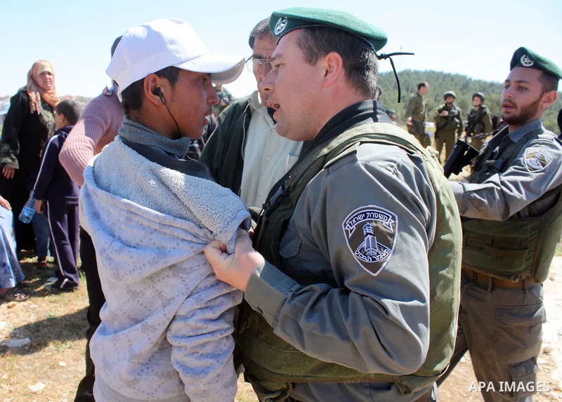 A Palestinian man quarrels with Israeli soldiers during a protest against Jewish settlers in the West Bank village of Yatta, south of the West Bank city of Hebron, on 26 March 2011.Photo by Najeh Hahlamoun