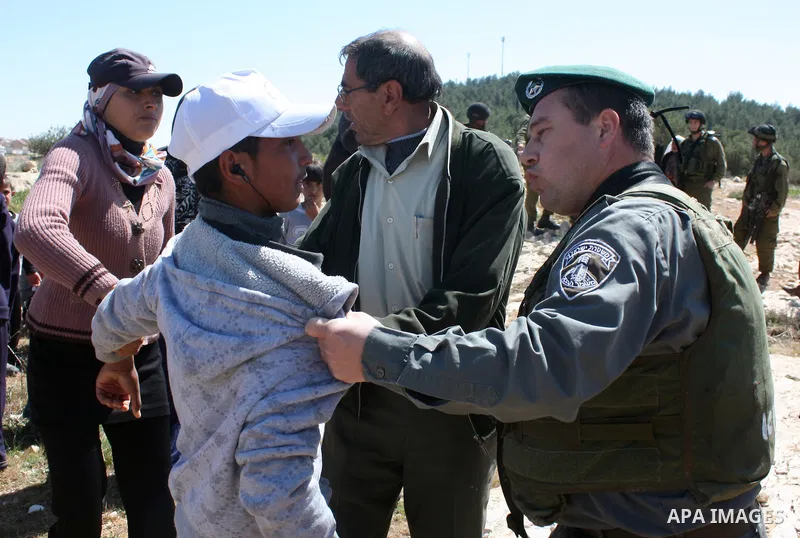 A Palestinian man quarrels with Israeli soldiers during a protest against Jewish settlers in the West Bank village of Yatta, south of the West Bank city of Hebron, on 26 March 2011.Photo by Najeh Hahlamoun