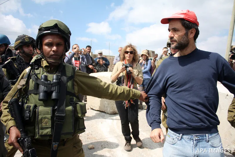 A Palestinian man quarrels with Israeli soldiers during a protest against Jewish settlers in the West Bank village of Yatta, south of the West Bank city of Hebron, on 26 March 2011.Photo by Najeh Hahlamoun