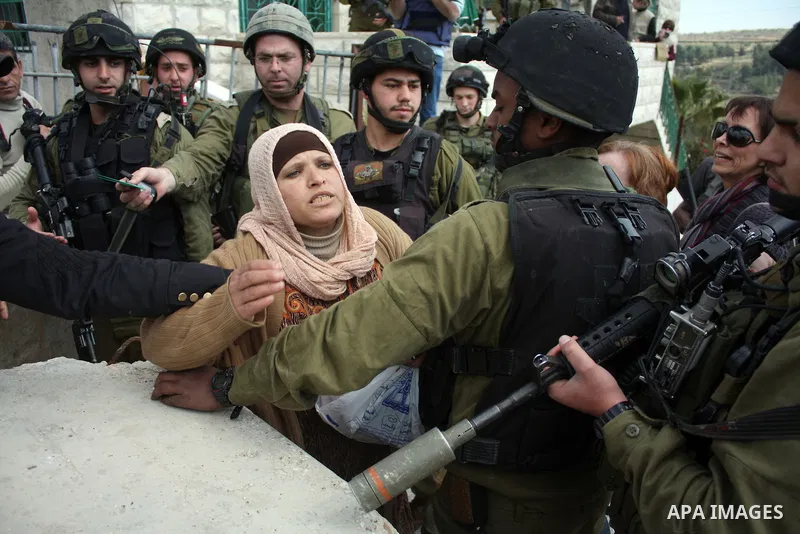 A Palestinian woman quarrels with Israeli soldiers during a protest against Jewish settlers in the West Bank village of Yatta, south of the West Bank city of Hebron, on 26 March 2011.Photo by Najeh Hahlamoun