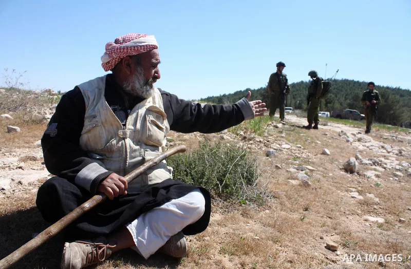 A Palestinian man quarrels with Israeli soldiers during a protest against Jewish settlers in the West Bank village of Yatta, south of the West Bank city of Hebron, on 26 March 2011.Photo by Najeh Hahlamoun
