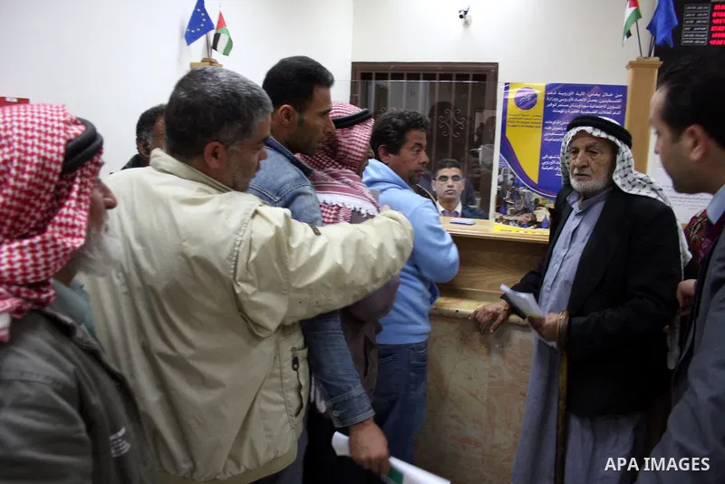 Palestinians receive the financial assistance from the Ministry of Social Affairs at a bank in the West Bank city of Salfit on March 26, 2011. Photo by Issam Rimawi