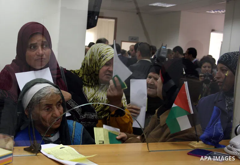 Palestinians receive the financial assistance from the Ministry of Social Affairs at a bank in the West Bank city of Salfit on March 26, 2011. Photo by Issam Rimawi