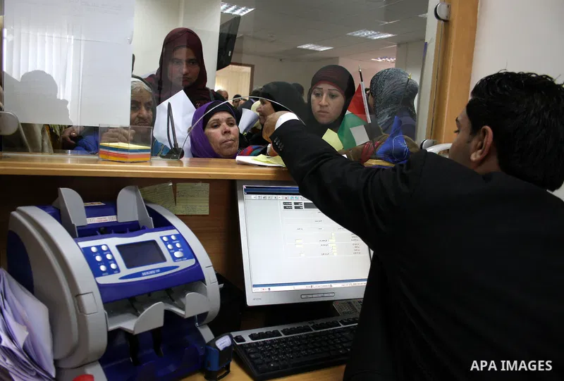 Palestinians receive the financial assistance from the Ministry of Social Affairs at a bank in the West Bank city of Salfit on March 26, 2011. Photo by Issam Rimawi