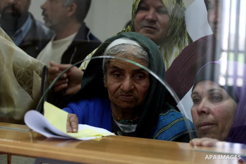 Palestinians receive the financial assistance from the Ministry of Social Affairs at a bank in the West Bank city of Salfit on March 26, 2011. Photo by Issam Rimawi