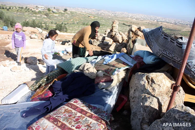 Palestinian family look for belongings from the rubble of their home after it was destroyed allegedly by Israeli army tractors early on 29 March 2011, in the West Bank village of Yatta near Hebron. The house was located...
