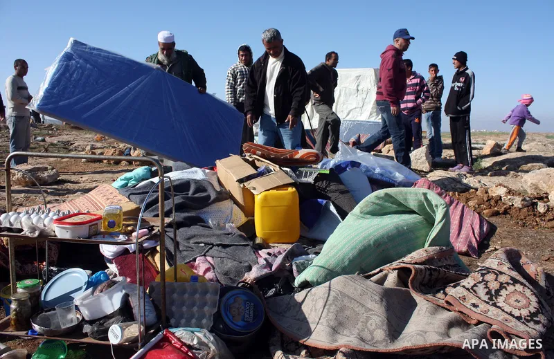 Palestinian family look for belongings from the rubble of their home after it was destroyed allegedly by Israeli army tractors early on 29 March 2011, in the West Bank village of Yatta near Hebron. The house was located...