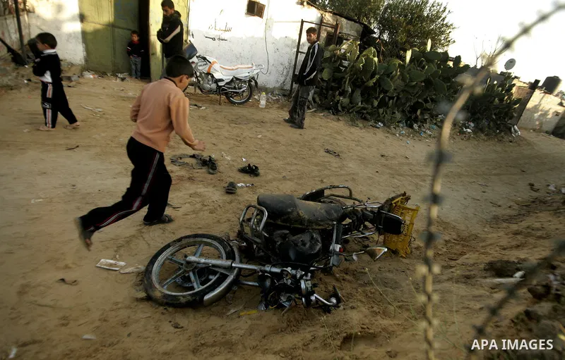 Palestinian boys stand next to the destroyed motorcycle that was ridden by Abu Mohammed Muammar and a fellow member of the Al-Quds Brigade, Islamic Jihad's armed wing, when they were hit by an Israeli warplanes strike in...