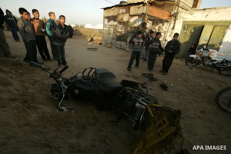 Palestinian boys stand next to the destroyed motorcycle that was ridden by Abu Mohammed Muammar and a fellow member of the Al-Quds Brigade, Islamic Jihad's armed wing, when they were hit by an Israeli warplanes strike in...