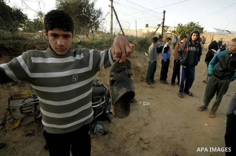 Palestinian boys stand next to the destroyed motorcycle that was ridden by Abu Mohammed Muammar and a fellow member of the Al-Quds Brigade, Islamic Jihad's armed wing, when they were hit by an Israeli warplanes strike in...