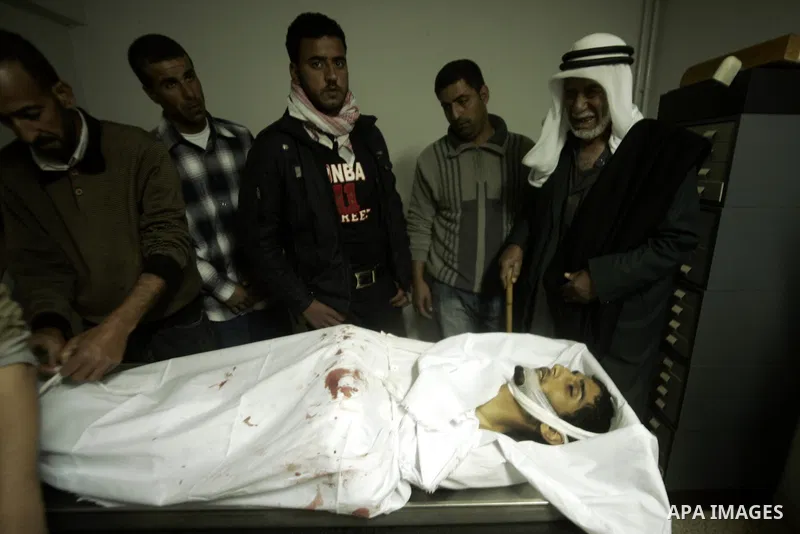 Palestinian relatives mourn over the body of Mohammed Muammar, who was killed during an Israeli air strike the previous day, in Khan Yunis, southern Gaza Strip, on March 30, 2011. The raid killed Muammar and wounded the...
