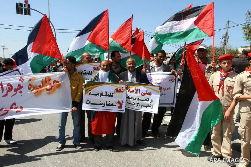 Palestinians wave their national flag and hold pictures of Palestinian prisoners jailed in Israel during a sit-in in Beit Hanun, northern Gaza Strip, on March 30, 2011 as hundreds of people across Israel and Palestinian...