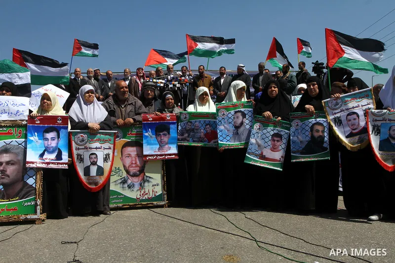 Palestinians wave their national flag and hold pictures of Palestinian prisoners jailed in Israel during a sit-in in Beit Hanun, northern Gaza Strip, on March 30, 2011 as hundreds of people across Israel and Palestinian...