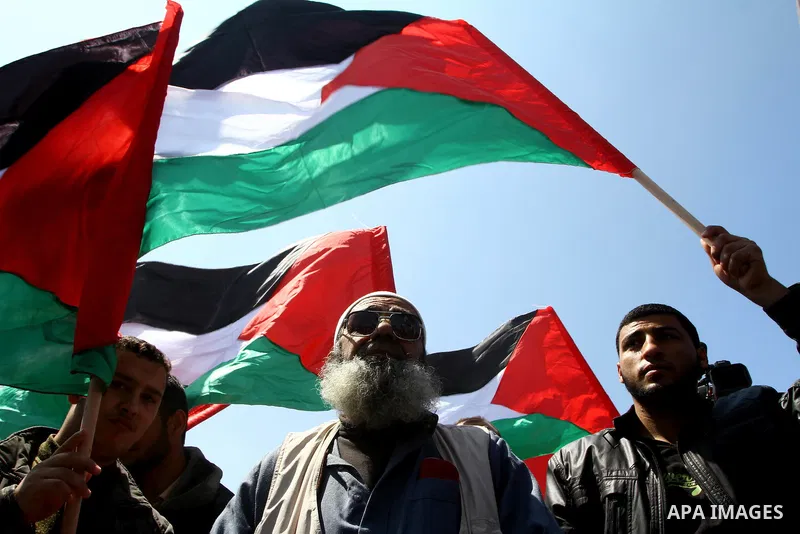 Palestinians wave their national flag and hold pictures of Palestinian prisoners jailed in Israel during a sit-in in Beit Hanun, northern Gaza Strip, on March 30, 2011 as hundreds of people across Israel and Palestinian...