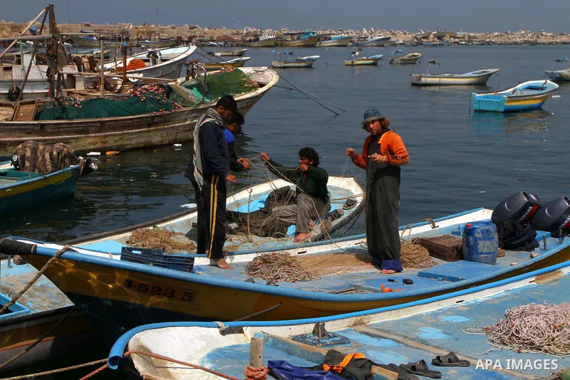 Palestinian fishermen fix their fishing nets at the port in Gaza City 30, 2011. Israel is considering building an artificial island with sea and air ports off blockaded Gaza, as a long-term solution to shipping goods int...