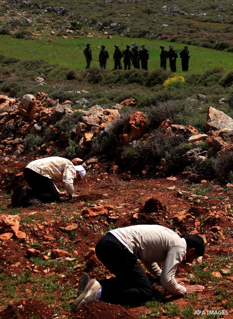 Israeli soldiers keep watch as Palestinians perform Friday prayers on an open field in the village of Qusra, near the Jewish settlement of Shilo, in the Israeli-occupied West Bank, on April 1, 2011. Photo by Wagdi Eshtay...