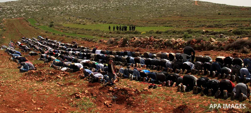 Israeli soldiers keep watch as Palestinians perform Friday prayers on an open field in the village of Qusra, near the Jewish settlement of Shilo, in the Israeli-occupied West Bank, on April 1, 2011. Photo by Wagdi Eshtay...
