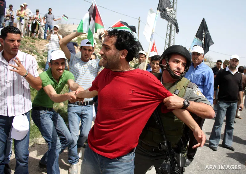 An Israeli border guard restrains a demonstrator during a protest against Israel's controversial separation barrier and to mark "Land Day" in the West Bank village of Maasarah, near the biblical town of Bethlehem, on Apr...