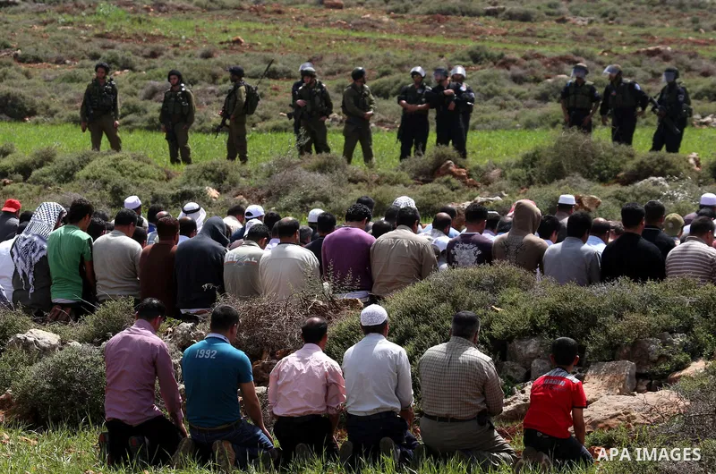 Israeli soldiers keep watch as Palestinians perform Friday prayers on an open field in the village of Qusra, near the Jewish settlement of Shilo, in the Israeli-occupied West Bank, on April 1, 2011. Photo by Wagdi Eshtay...