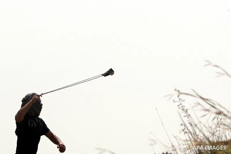 Palestinian demonstrators hurl stones towards Israeli forces during clashes following a weekly demonstration against Israel's separation barrier in the Palestinian West Bank village of Bilin on April 01, 2011. Photo by I...