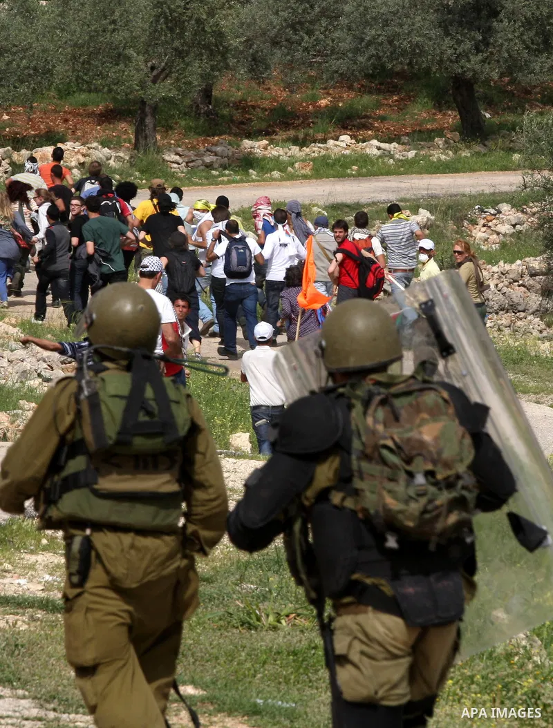 Israeli forces run behind demonstrators during clashes following a weekly demonstration against Israel's separation barrier in the Palestinian West Bank village of Bilin on April 01, 2011. Photo by Issam Rimawi