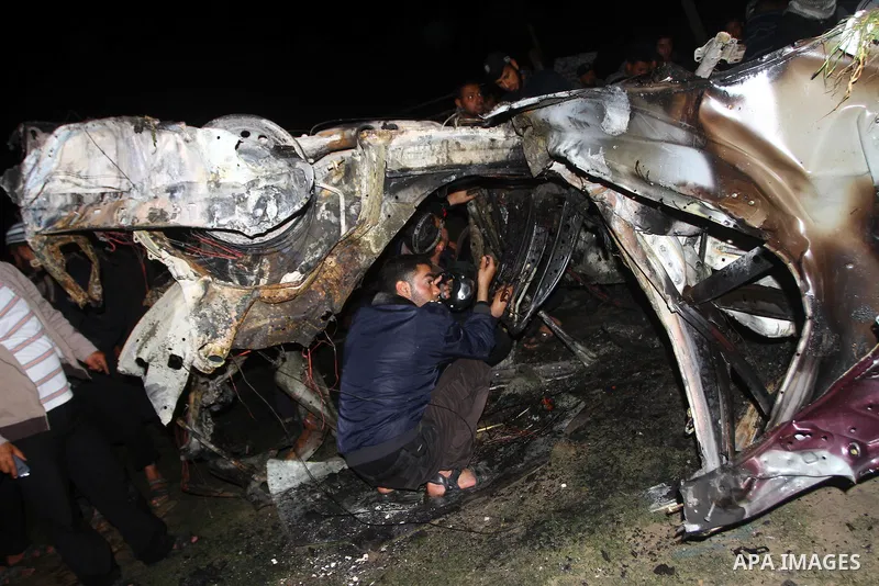 Members of Hamas' security forces inspect a car after an Israeli air strike in Deir Al-Balah in the central Gaza Strip early April 2, 2011. Israeli aircraft killed three Palestinian gunmen in the southern Gaza Strip earl...