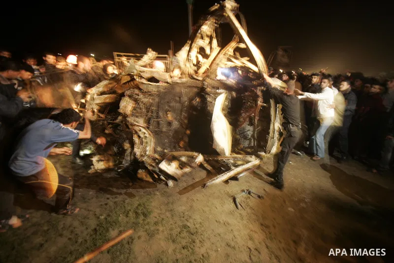 Palestinians surround the wreckage of a vehicle following an Israeli airstrike that killed three of Hamas militants near Deir Al Balah, central Gaza Strip, early Saturday, April 2, 2011. Israeli aircraft killed the milit...