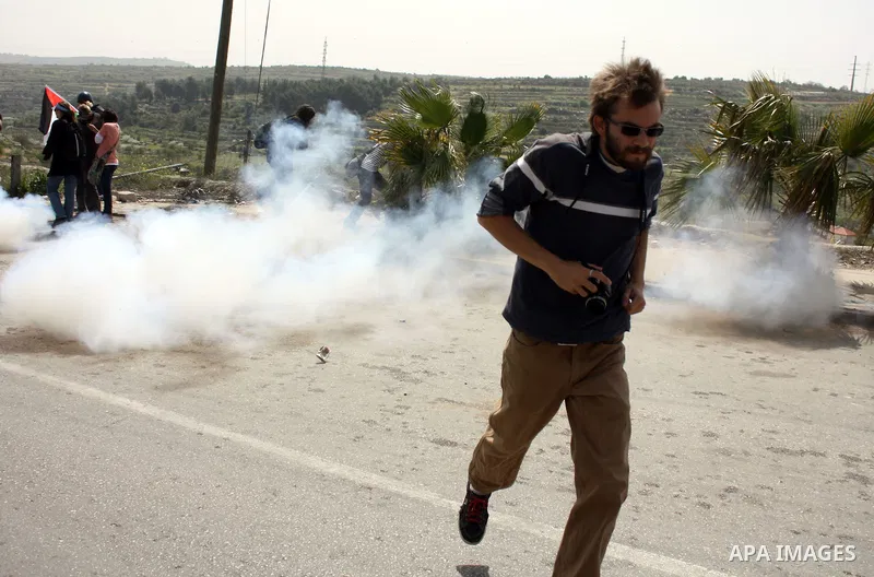 A demonstrator run for cover from tear gas fired by Israeli soldiers during a protest by foreign, Israeli and Palestinian demonstrators against the controversial Israeli separation barrier, in the Palestinian village of...