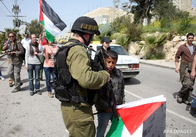 A Palestinian boy argues with Israeli soldiers during a protest by foreign, Israeli and Palestinian demonstrators against the controversial Israeli separation barrier, in the Palestinian village of Beit Omar, near the We...